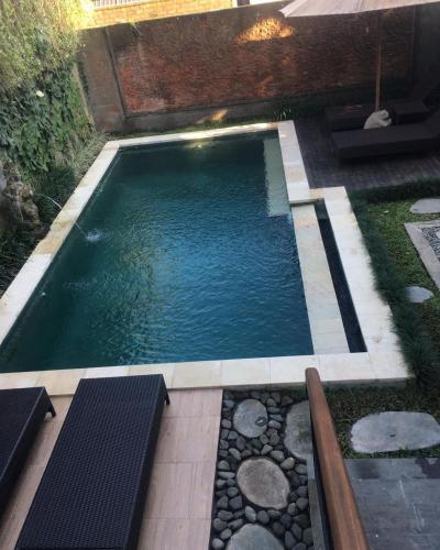 a small swimming pool with rocks in a backyard at Heaven Villa Ubud in Ubud