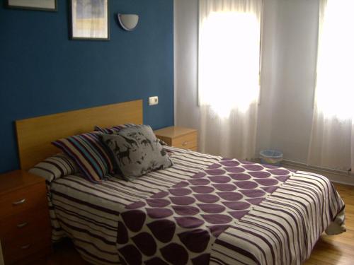 a bedroom with a bed with blue walls and a window at Pensión Gema in Irún