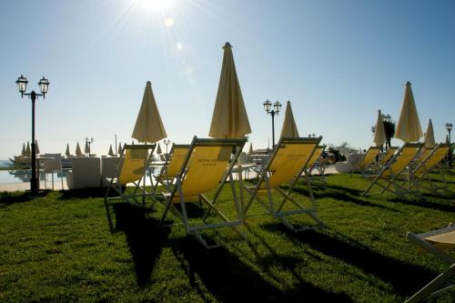a row of yellow chairs and umbrellas on the grass at Roses Hotel in Roseto degli Abruzzi