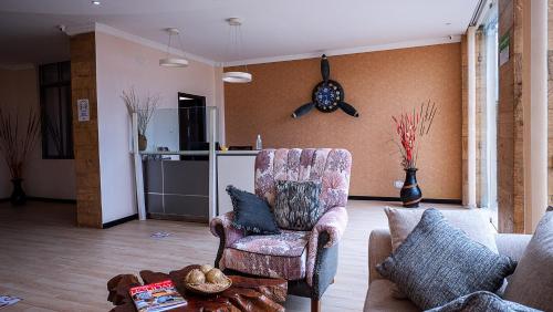 a living room with a chair and a clock on the wall at The Nest Boutique Hotel in Naivasha