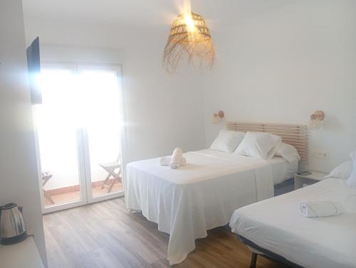 アルメリアにあるHOSTAL CASA EMILIOの白い部屋で、ベッド2台、窓が備わります。