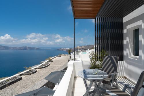 a balcony with a table and chairs overlooking the water at Santorini Princess Spa Hotel in Imerovigli