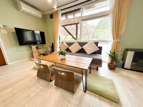 a living room with a table and a couch at Haru's House Onsen モール温泉付き in Shiraoi