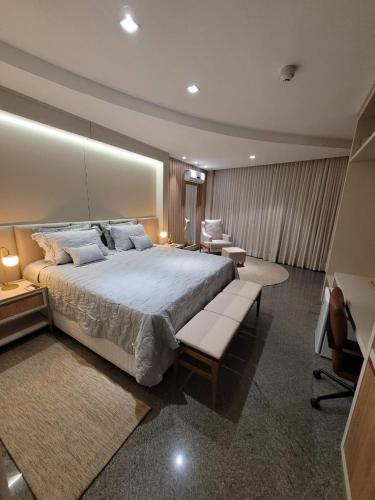 a large bedroom with a large bed and chairs at Lindóya Hotel in Catalão
