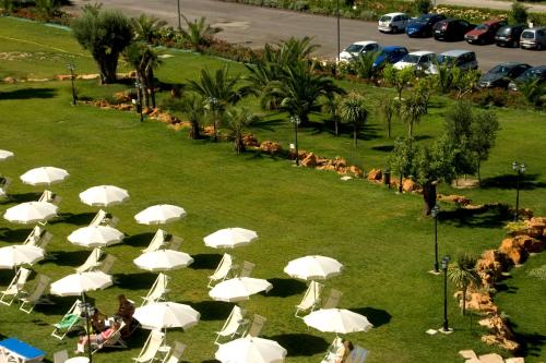 a group of white chairs and umbrellas on the grass at Roses Hotel in Roseto degli Abruzzi
