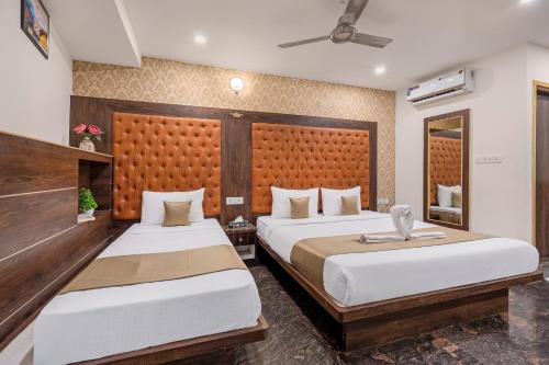a bedroom with two beds and a headboard at Hotel Classio Koramagala in Bengaluru