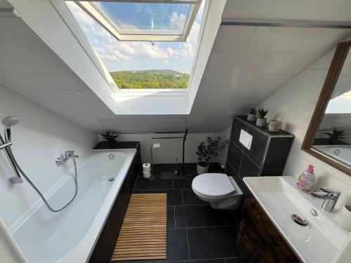 a bathroom with a tub and a toilet and a skylight at Moderne Ferienwohnung Iserlohn in Iserlohn
