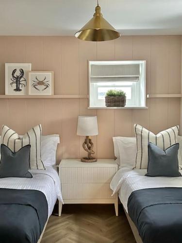 a room with two beds with pillows and a window at Tobias Apartment, 2 Bedroom, Aberaeron in Aberaeron