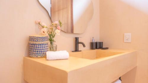 a bathroom with a sink with a mirror and flowers at La Alberca Hotel Boutique in Mazunte