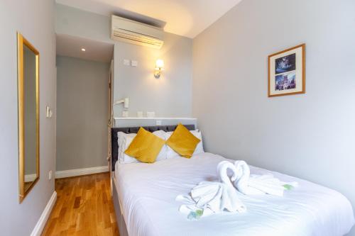 a bedroom with a white bed with towels on it at Coronation Hotel in London