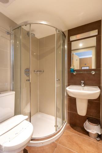 a bathroom with a shower and a toilet and a sink at Coronation Hotel in London