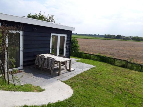 a small shed with a table and chairs next to a field at Strandhuis De Bakkeete B in Kamperland