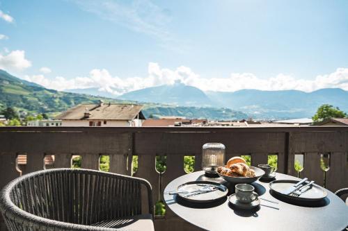 a table with a bowl of food on a balcony at LUXE VISTA City Apartments Algund in Lagundo