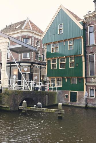 a green building next to a river with buildings at Huis met de Kogel in Alkmaar