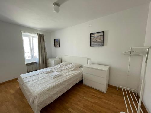 a white bedroom with a bed and a dresser at Apartment Tartini in Piran