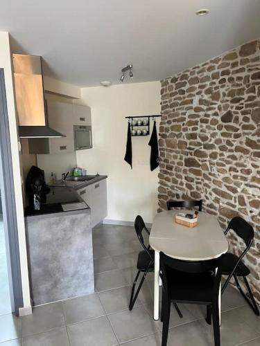 - une cuisine avec une table et un mur en pierre dans l'établissement Maisonnette charmante 4 personnes proche de Vannes, à Grand-Champ
