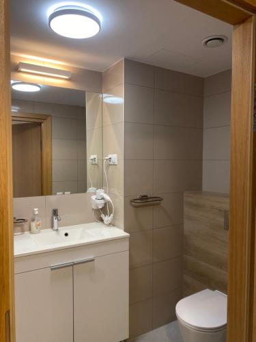 ein Badezimmer mit einem Waschbecken, einem WC und einem Spiegel in der Unterkunft Seaside Park Apartament z widokiem na morze in Kołobrzeg