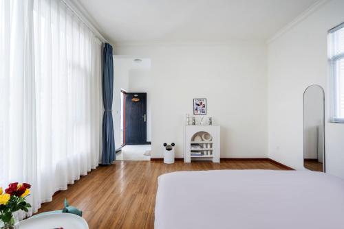 a bedroom with white walls and blue curtains at 渔月撸猫客栈-大理古城店 in Dali
