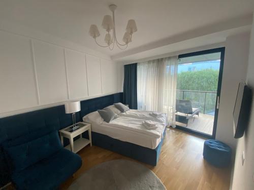 ein Schlafzimmer mit einem Bett und einem blauen Sofa in der Unterkunft Seaside Park Apartament z widokiem na morze in Kołobrzeg