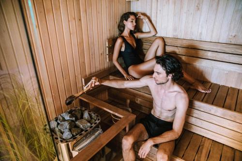 a man and a woman sitting in a sauna at Ilirija Resort Hotel Adriatic in Biograd na Moru