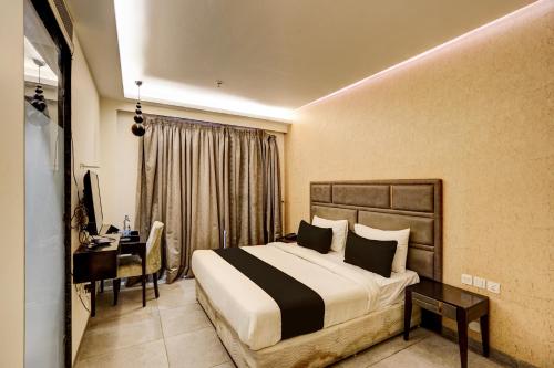 a hotel room with a bed and a desk and a computer at Super Townhouse Rohini Near Paschim Vihar Metro Station in New Delhi