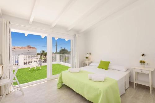 a white bedroom with two beds and a balcony at Villa Molly 16 by Villa Plus in Punta Prima