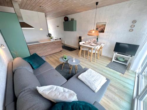 a living room with a gray couch and a table at Agger Tange Feriecenter lejligheder - 100 m fra Vesterhavet in Vestervig