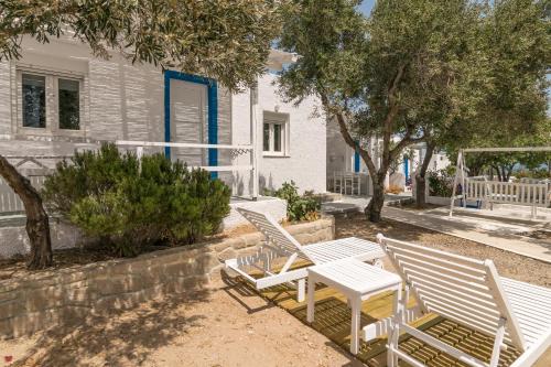 three white chairs and a table in front of a house at Summer Residence in Provatas