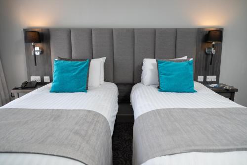 two beds in a hotel room with blue pillows at Hawkstone Park in Wem