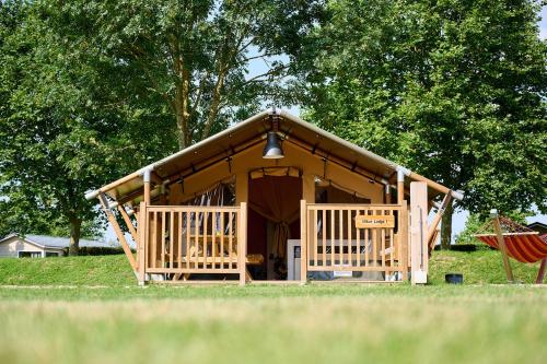a log cabin with a porch and a swing at Safaritenten Betuwe in Kesteren