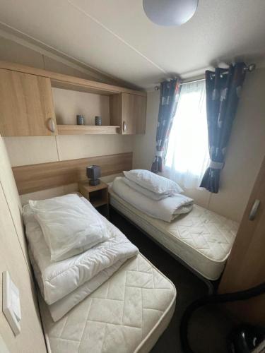 two beds in a small room with a window at Lyons robin hood caravan 43SW in Rhyl