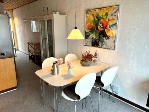 a table and chairs in a kitchen with a painting on the wall at Agger Tange Feriecenter lejligheder - 100 m fra Vesterhavet in Vestervig