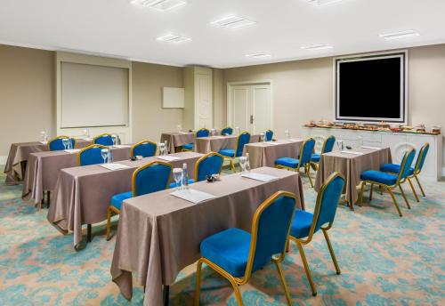 a conference room with tables and chairs and a screen at Kaya İstanbul Fair & Convention in Istanbul