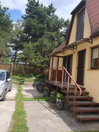 a house with a porch and a car parked next to it at Лора in Lapmežciems