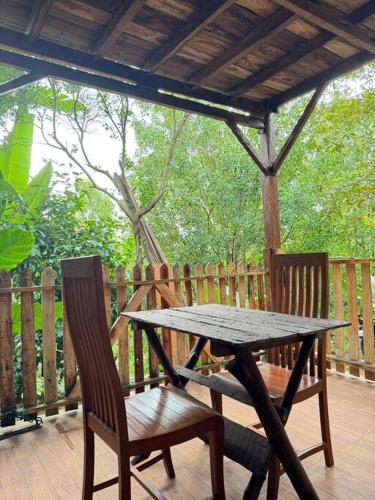 una mesa de madera y sillas en una terraza de madera en De-Ranggon Home stay garden huts, en Gitgit