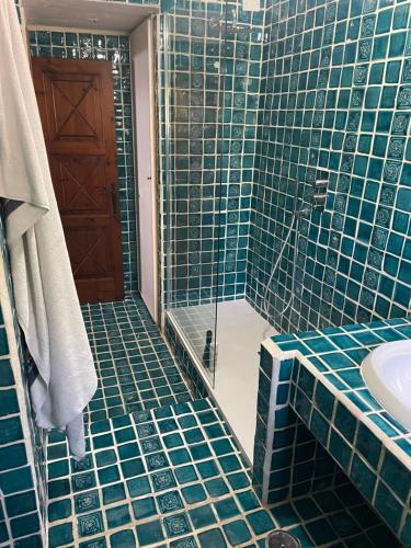 een blauw betegelde badkamer met een douche en een wastafel bij Villa Bianca, piscina e panorama in Torre delle Stelle