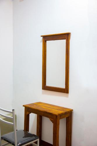 a mirror on a wall with a table and a chair at SkyAvenue Guest House in Kadawatha