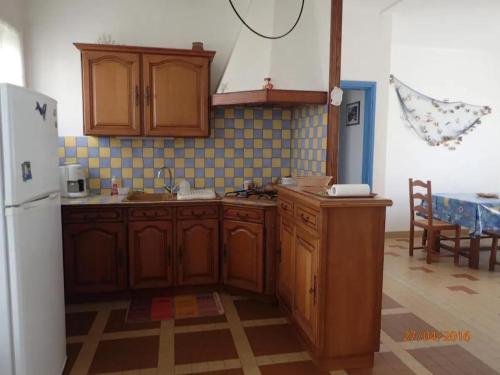 une cuisine avec des armoires en bois et un réfrigérateur blanc dans l'établissement Maison confortable à Saint-Hilaire-de-Riez avec jardin clôturé, à Saint-Hilaire-de-Riez