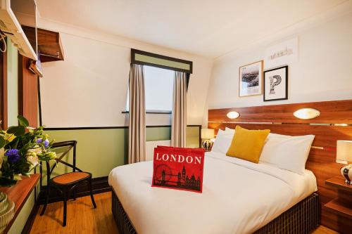 a hotel room with a bed with a sign on it at Huttons Hotel, Victoria London in London