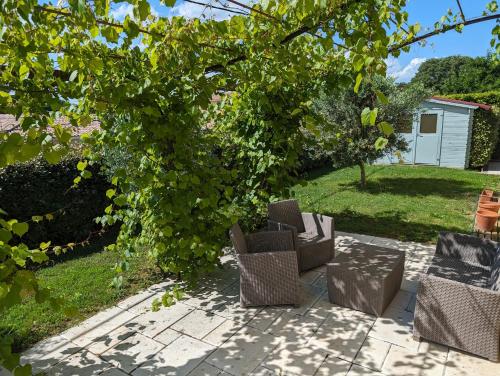 un groupe de chaises assises sur une terrasse sous un arbre dans l'établissement Villa victoria, à Cornillon