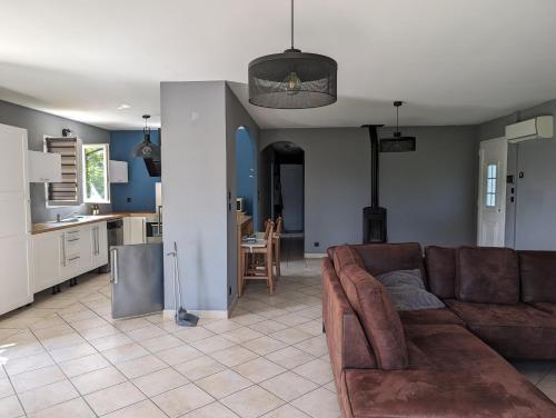 un salon avec un canapé marron et une cuisine dans l'établissement Villa victoria, à Cornillon