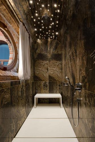 a bathroom with a shower with a bench in it at Hyatt Centric Murano Venice in Murano
