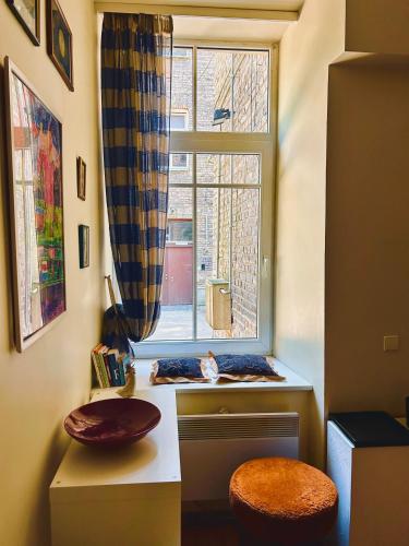 a room with a window with a cat sitting on a stool at Guest room in Old Town in Vilnius