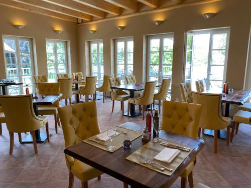 a dining room with tables and chairs and windows at Hotel BonaMari in Salzgitter