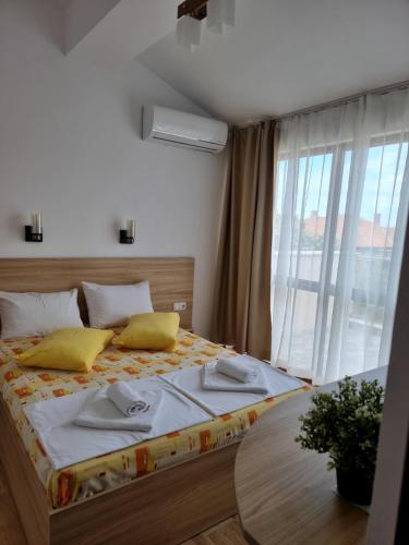 a bedroom with a bed with yellow pillows and a table at Vila Mihnevi in Chernomorets