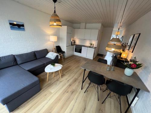 a living room with a blue couch and a table at Agger Tange Feriecenter lejligheder - 100 m fra Vesterhavet in Vestervig
