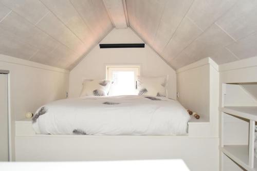 a white bed in a white room with a window at Kibbelschuur in Zottegem