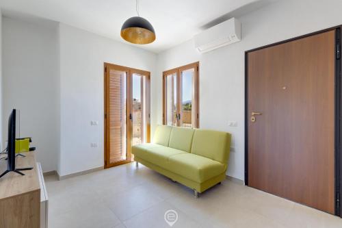 a living room with a green chair and a door at Lemon Apartment 2 in Àrbatax