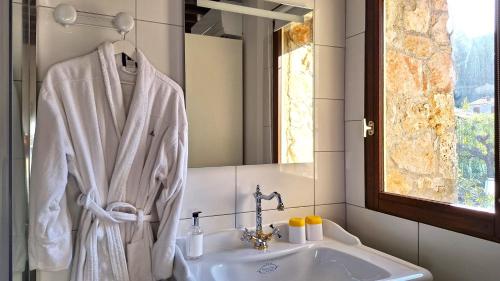 La salle de bains est pourvue d'un peignoir blanc suspendu à côté d'un lavabo. dans l'établissement La Bergerie Du Moulin, à Taradeau