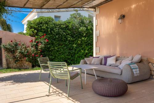 a patio with a couch and two chairs and a table at Villa Bouganville con piscina by Wonderful Italy in Siracusa